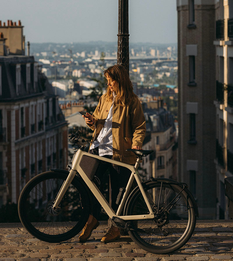 Eine Frau nutzt den herausnehmbaren Akku des LEMMO E-Bikes zum Aufladen ihres Handys